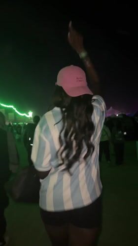 Person in striped shirt, pink cap walks through Indio crowd