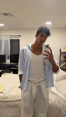 Young man takes mirror selfie while adjusting shirt in Palm Springs
