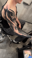 Tattooed man seated in office chair captured indoors