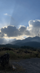 Dramatic sunlight illuminates Kintamani mountains through cloudy Indonesian skies
