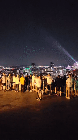 Nighttime crowd takes in the Montreal skyline from an overlook