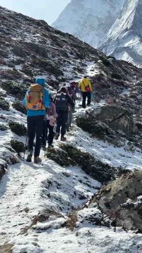 Hikers ascend snowy mountain trails in Nepal's Khumjung region