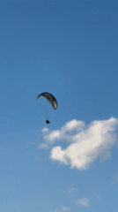 Tandem paraglider soars over Fethiye coastline under clear skies