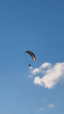 Tandem paraglider soars over Fethiye coastline under clear skies