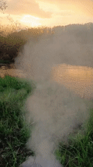 Burn barrel smokes on Motyakovo riverbank during sunset