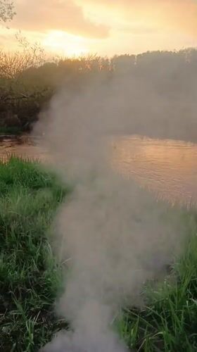 Burn barrel smokes on Motyakovo riverbank during sunset