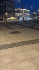 Woman walks urban street amid illuminated high-rises at evening