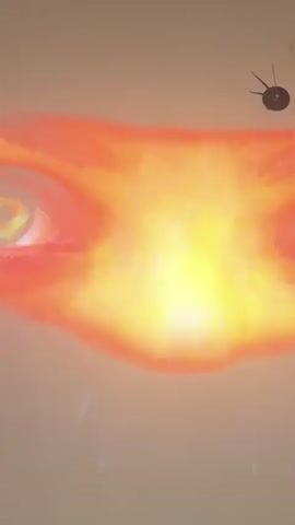The video displays a projection on a plain wall, featuring abstract, colorful visuals that shift and morph. Initially, a close-up of a human eye with a fiery orange glow is visible. This transitions to streaks of electric blue light forming a symmetrical pattern. The projection then shows two large, orb-like shapes in varying shades of blue with speckles of light. Following this, a green, swirling nebula-like formation resembling an eye appears. The video concludes with a bright, pulsating pink and blue abstract pattern. A black clock with three hands is mounted on the wall in the upper right corner of the frame, remaining static throughout the recording. The wall itself appears to be a neutral, light-colored surface. There are no discernible people or actions beyond the projection itself.