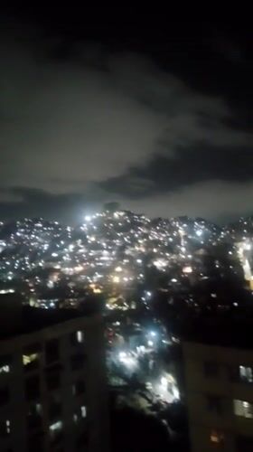 Nighttime aerial view captured of illuminated Caracas cityscape
