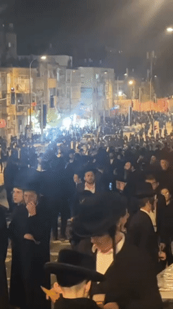 Orthodox Jewish men gather on Jerusalem street at night