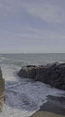 Rocky Saint-Nazaire shoreline with waves, a ship, and chalk art