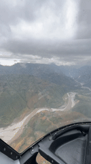 Aircraft flies over mountainous Nepal region under overcast skies