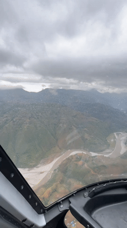 Aircraft flies over mountainous Nepal region under overcast skies