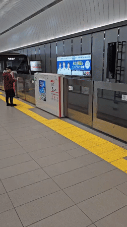 Silver train with red stripe passes through Osaka subway station