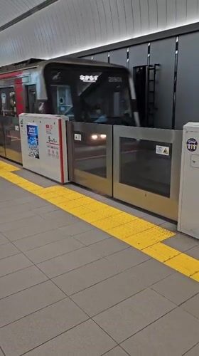 Silver train with red stripe passes through Osaka subway station