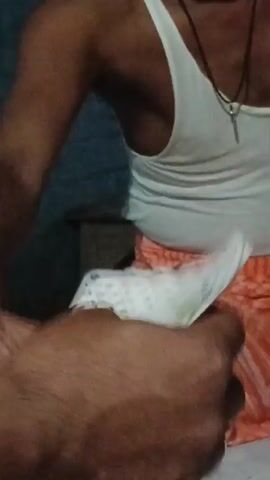The video begins with a close-up shot of a person's hands holding a deck of playing cards. The person is wearing a white tank top and orange shorts. The cards are fanned out, revealing several face cards, including Jacks and Queens, with some suit symbols visible. The background is blurred, but it appears to be an indoor setting with a light-colored surface, possibly a bed or a table. The person's fingers are manipulating the cards. The focus then shifts to the person's hand, showing the back of their fingers and thumb. The video ends with a close-up of the person's hand.