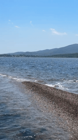 Half-submerged gravel causeway draws walkers into the sea