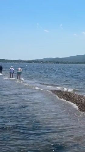 Half-submerged gravel causeway draws walkers into the sea