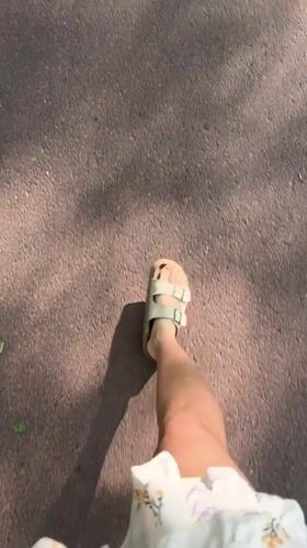 Person in floral dress walks through Scolkovo wearing sandals