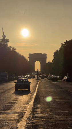 Evening traffic flows past Arc de Triomphe in Paris