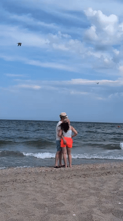 Couple embraces on Constanța beach, waves breaking nearby