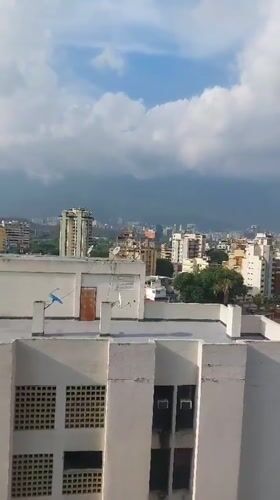 Panoramic daytime view captures Caracas cityscape against mountain backdrop