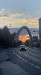 Arched bridge at golden hour, traffic rolling through