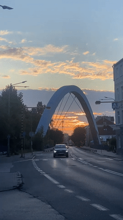 Arched bridge at golden hour, traffic rolling through