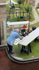 Man cuts white material with power tool in Great Yarmouth backyard