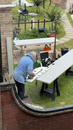 Man cuts white material with power tool in Great Yarmouth backyard