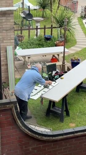 Man cuts white material with power tool in Great Yarmouth backyard