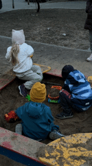 Children play in sandbox and draw with chalk in Moscow