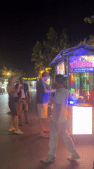 Street karaoke stall draws nighttime crowd, woman performs