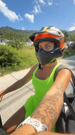 Motorcycle rider in neon green cruising Ko Samui's tree-lined roads