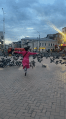 Person in pink coat scatters pigeons near Kazan station