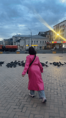 Person in pink coat scatters pigeons near Kazan station