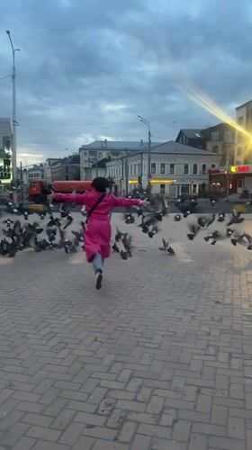 Person in pink coat scatters pigeons near Kazan station