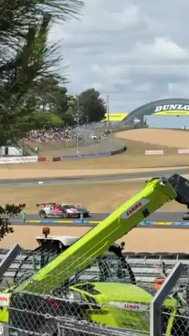 Here is a description of the video:

The video shows race cars speeding around a track on what appears to be a sunny day, with a race underway. 

In the first scene, a crane is visible on the left side of the screen, alongside fencing and a portable restroom. The race track extends towards the horizon and is partially surrounded by a tire wall, with a race car driving by on the track.  In the background, an archway can be seen with the word "DUNLOP" printed on it.  Spectators are seated in the distance behind the track.

In the subsequent scenes, a race car travels by on the race track.  The track is bordered by a concrete retaining wall, behind which a large crowd of spectators is seated in stands. An advertisement for "CADILLAC" is written on the retaining wall.