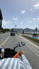Motorcyclist with child rides beachfront road in Fethiye, Turkey