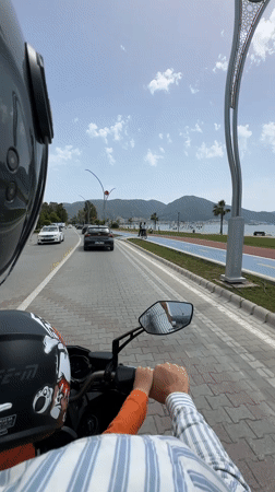 Motorcyclist with child rides beachfront road in Fethiye, Turkey