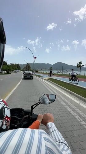 Motorcyclist with child rides beachfront road in Fethiye, Turkey