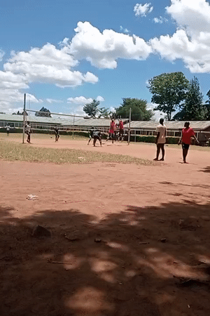 Young people play volleyball on dirt court in Kenya