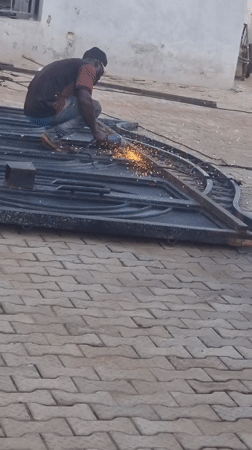 Man grinds metal gate outside building, sparks fly