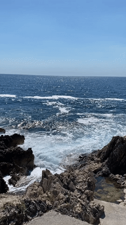Tattooed woman enjoys afternoon at rocky Montenegro coastline
