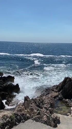 Tattooed woman enjoys afternoon at rocky Montenegro coastline