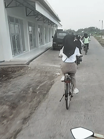 Four cyclists ride concrete path in Gadingan, Indonesia