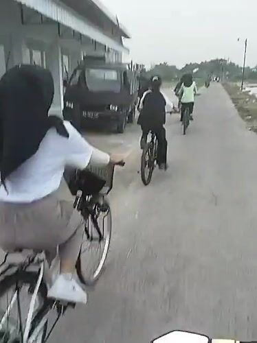 Four cyclists ride concrete path in Gadingan, Indonesia