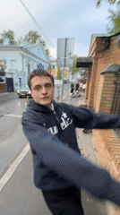Young man gestures on wet Moscow street near fence