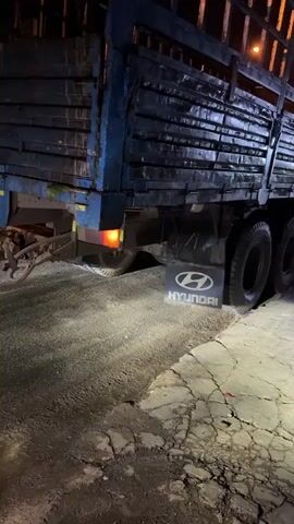The video shows the back of a blue Hyundai truck parked at night, and the interior of a vehicle. The truck has a wooden slat cargo bed. The interior of the vehicle is brightly lit with neon lights and shows several seats and a box labeled "Sanna." There are personal belongings scattered around.