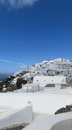 Clear skies frame Santorini's whitewashed buildings in morning view